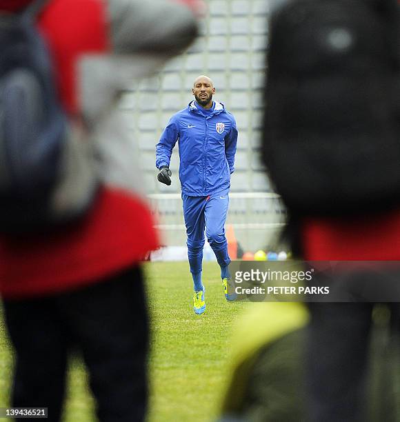 Photographers shoot French striker Nicolas Anelka as he warms up before his team Shanghai Shenhua plays in a friendly match against Hunan Xiangtao at...