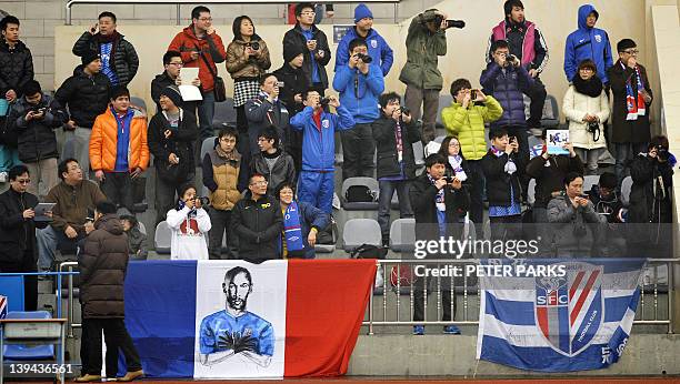 Fan watch as French striker Nicolas Anelka warms up with teammates before his team Shanghai Shenhua plays in a friendly match against Hunan Xiangtao...