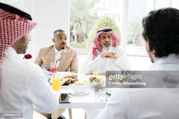 riyadh businessmen conversing over lunch in restaurant - middle east friends stock pictures, royalty-free photos & images