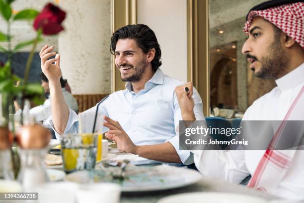 saudi men smiling and gesturing during lunchtime discussion - arab dinner table stock pictures, royalty-free photos & images