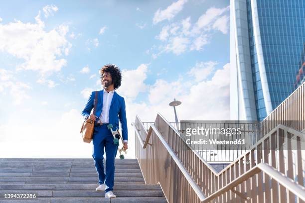 smiling businessman with skateboard walking down on staircase - guy looking down stock pictures, royalty-free photos & images