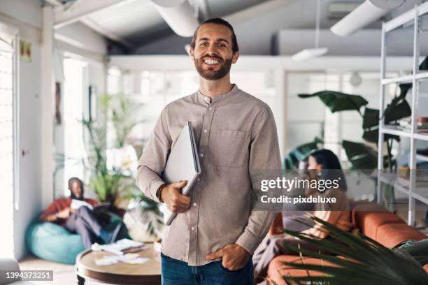 young happy businessman standing in an office at work - standing with laptop imagens e fotografias de stock