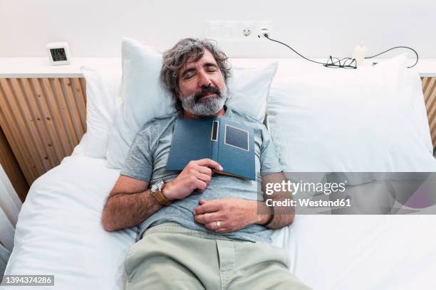 senior man sleeping with book on bed at home - westend61 fotografías e imágenes de stock