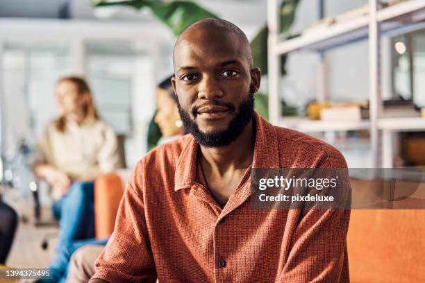 giovane uomo d'affari africano seduto in un ufficio al lavoro - office portrait uomo foto e immagini stock