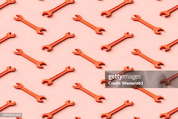 three dimensional pattern of rows of orange colored wrenches flat laid against beige background - open end spanner stock illustrations