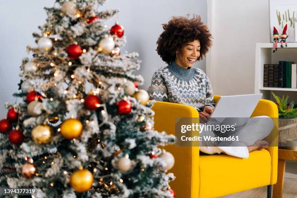 happy woman using laptop sitting on armchair at home - christmas background no people stock pictures, royalty-free photos & images
