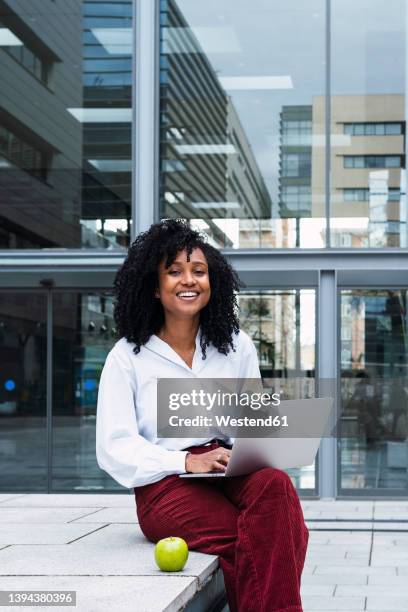 happy businesswoman sitting with laptop at office park - apple laptop stock pictures, royalty-free photos & images