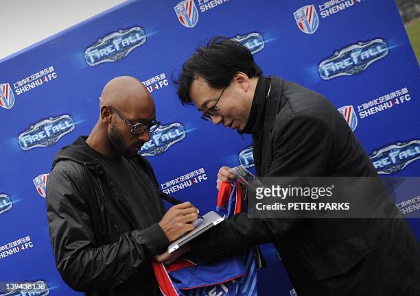 French striker Nicolas Anelka signs an autograph on a fans iPad after his team Shanghai Shenhua played a friendly match against Hunan Xiangtao at...