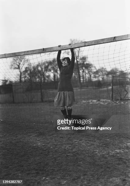 Player of the all-women team of staff of one of the J Lyons' Corner Houses hanging from a football goal at a soccer match between the two branches...
