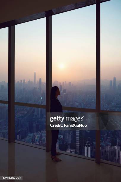 young woman in suit looks at shenzhen skyline from window in building - corporate skyline stock pictures, royalty-free photos & images