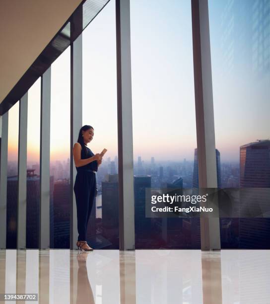 chinesische geschäftsfrau mit smartphone mit stadtbild im korridor des einkaufszentrums - mobile phone reading low angle stock-fotos und bilder