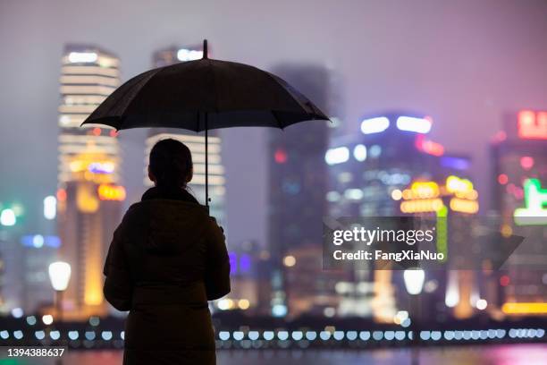 person standing with umbrella in rain at night, shanghai - holding umbrella stock pictures, royalty-free photos & images