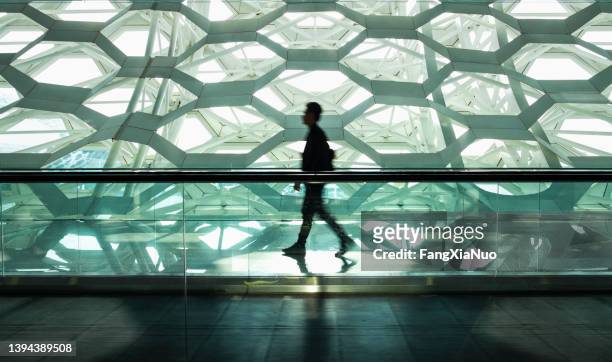 hombre caminando solo en el pasillo del pasillo moderno - expectativas fotografías e imágenes de stock