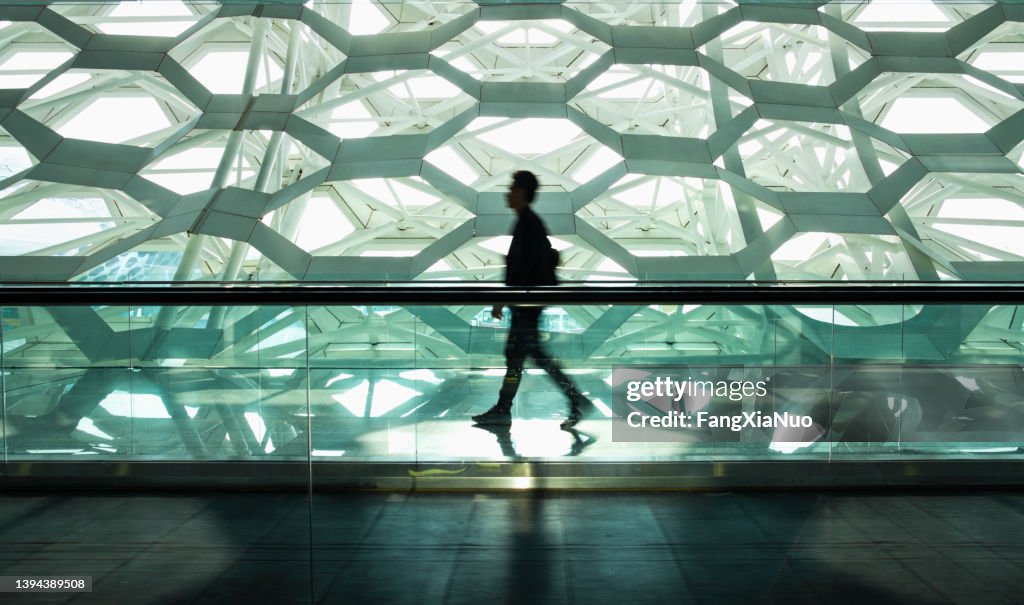 Man walking alone in modern corridor hallway