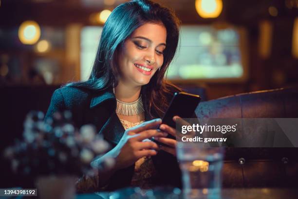 une femme d’affaires se détend et utilise un smartphone dans un restaurant. - human mouth stock photos et images de collection