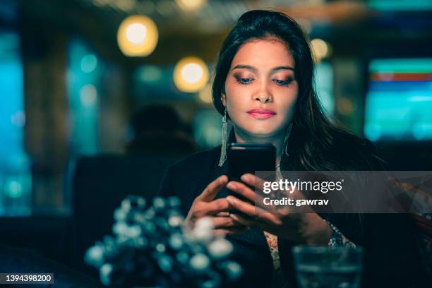 geschäftsfrau entspannt sich und benutzt ein smartphone in einem restaurant. - ohrhänger stock-fotos und bilder