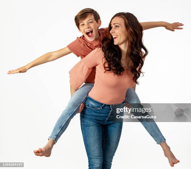 mother giving her son a piggy back ride - boy jeans stock pictures, royalty-free photos & images