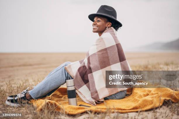 young black women wrapped with blanket on the beach - wrapped in a blanket stockfoto's en -beelden