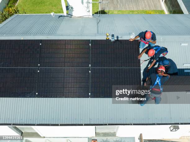 team of workers install solar panels on the roof of a house being built - south africa aerial stock pictures, royalty-free photos & images