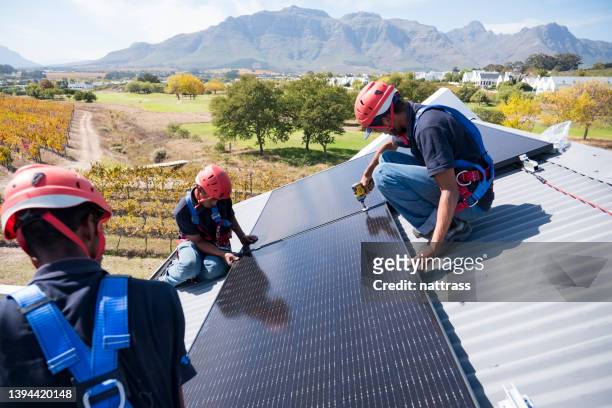 trabajadores calificados conectan e instalan paneles solares - africa fotografías e imágenes de stock