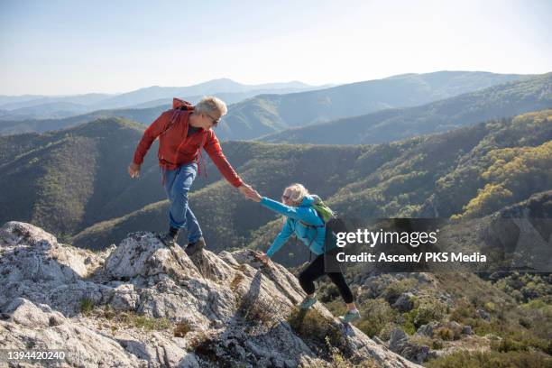 senior hiking couple ascend mountain ridge - eskapismus stock-fotos und bilder