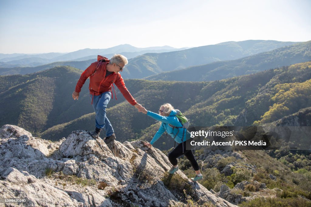 Senior hiking couple ascend mountain ridge