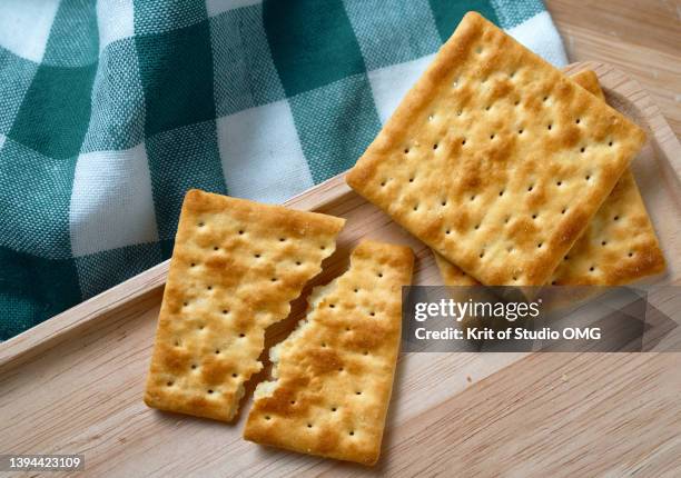 cracked wholegrain cracker on the wooden tray - crackers stock pictures, royalty-free photos & images