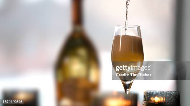 champagne being poured into a glass. - champagner gläser mit flasche unscharfer hintergrund stock-fotos und bilder