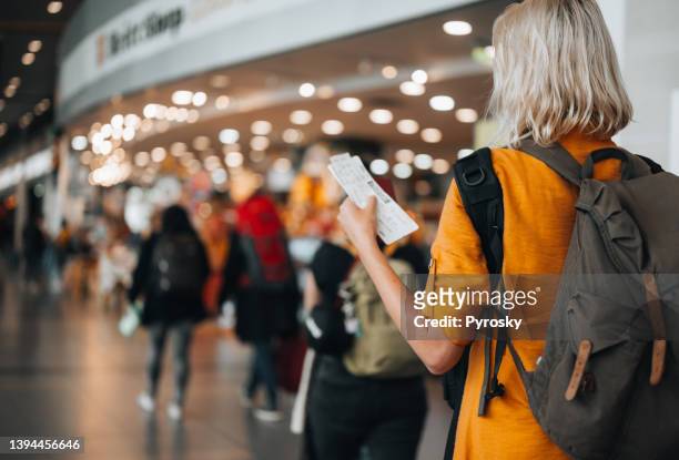a woman at the airport holding a passport with a boarding pass - ticket stock pictures, royalty-free photos & images