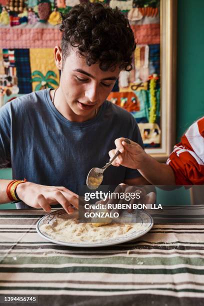 front view of smiling caucasian adolescence man preparing homemade croquettes with fingers. food and drink concept. - gonzalo caballero fotografías e imágenes de stock