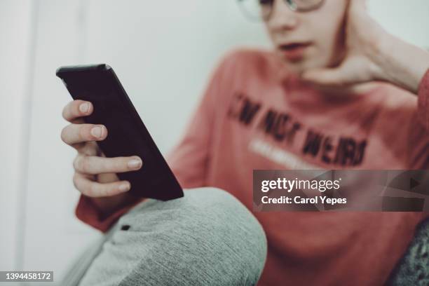 relaxed male hispanic teenager texting on mobile phone - zoom app stock pictures, royalty-free photos & images