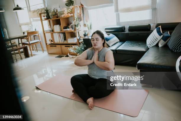 e-learning with yoga, asian overweight woman training yoga at home with online class. - connected mindfulness work stock pictures, royalty-free photos & images