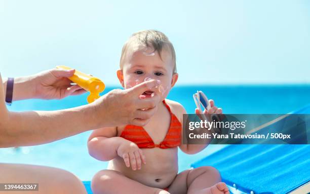 mother puts sunscreen on baby selective focus - baby suncream stock pictures, royalty-free photos & images