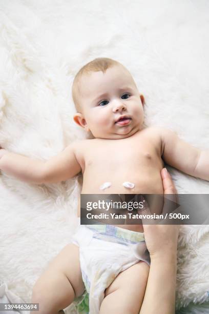 mother puts cream on little baby selective focus - massage funny stock pictures, royalty-free photos & images