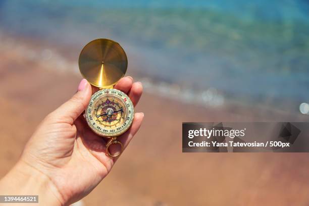 compass in hand against the background of the sea selective focus - compass north foto e immagini stock