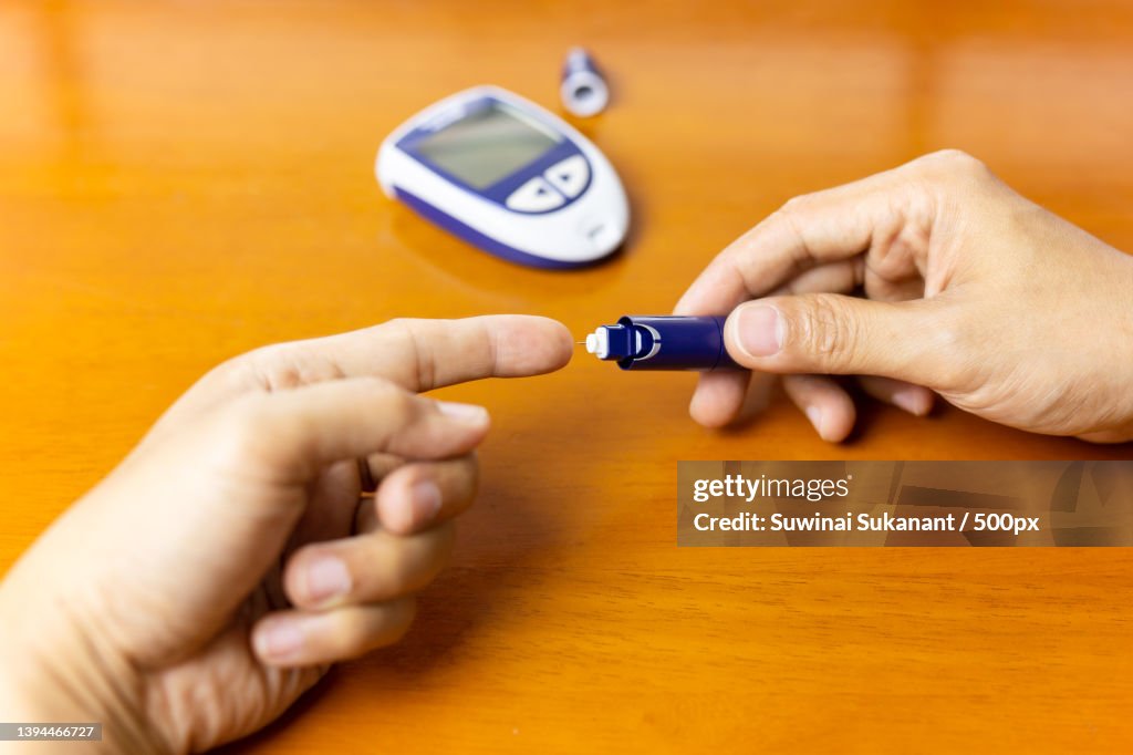 Man using lancelet on finger checking blood sugar level,Thailand