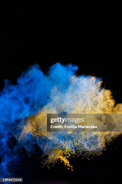 yellow and blue dust splash - farbpulver stock-fotos und bilder