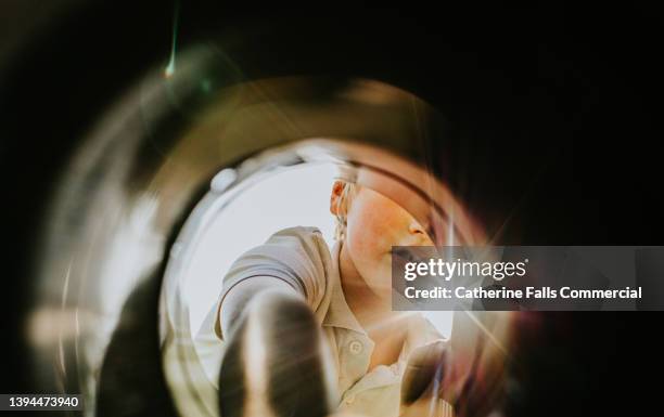 a young boy looks into a container with curiosity, he reaches far inside - on the outside looking in stock pictures, royalty-free photos & images