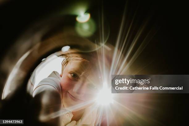 a cute young boy looks into a container with curiosity, and smiles as he reaches inside - raffle stock-fotos und bilder