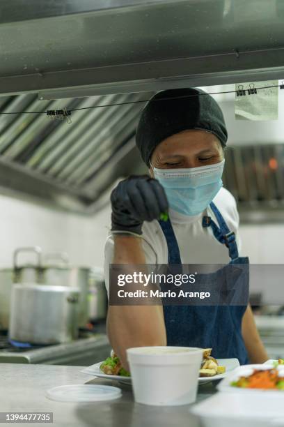 latin woman cook by profession prepares food in the restaurant where she works - restaurant mask stock pictures, royalty-free photos & images