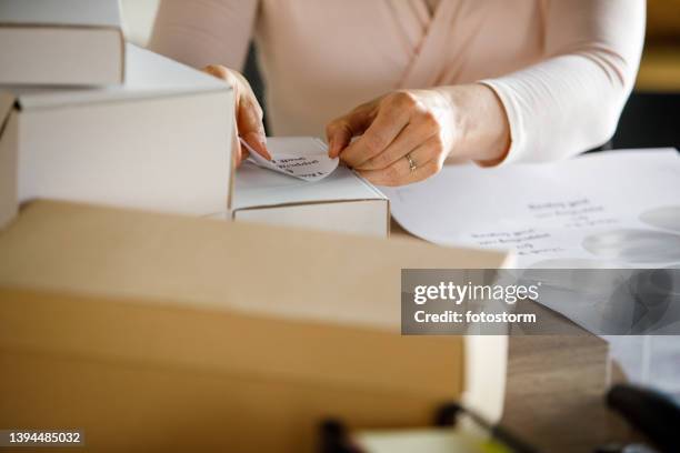 selective focus shot of unrecognizable businesswoman applying a label on a package - labelling stock pictures, royalty-free photos & images