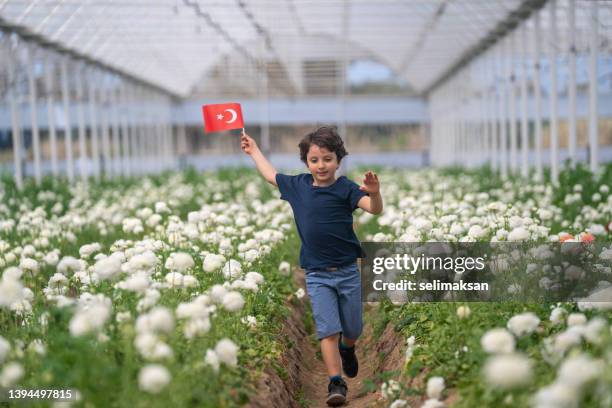 foto de un niño de primaria sosteniendo la bandera turca y corriendo en el jardín de flores - bandera turca fotografías e imágenes de stock