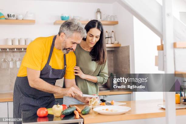 彼らの台所に行くために野菜を準備する成熟したカップル - middle aged couple cooking ストックフォトと画像