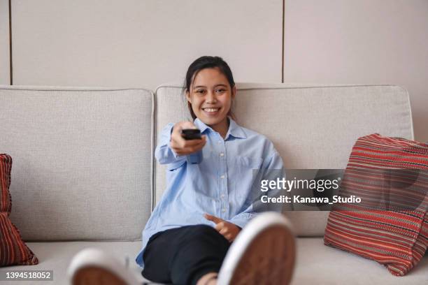 cheerful young asian woman binge watching tv series - binge tv stockfoto's en -beelden