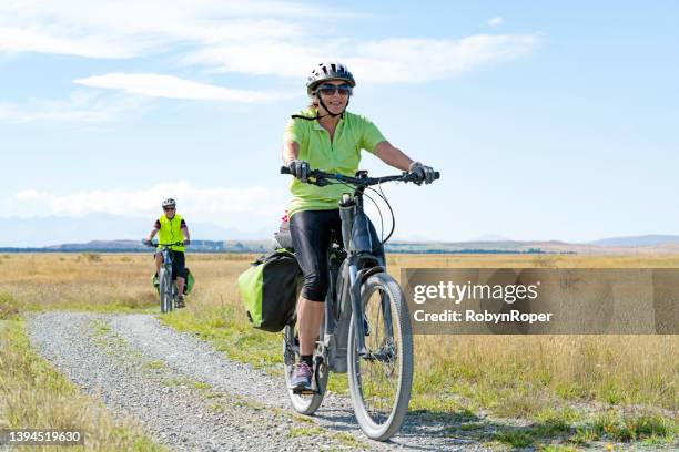 mature couple ride electric mountain bikes - elektrische fiets stockfoto's en -beelden