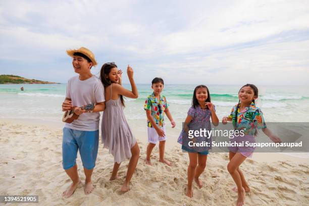 asian father and his family playing guitar on the beach. holiday and relaxation concept. - 20 years old dancing stock pictures, royalty-free photos & images