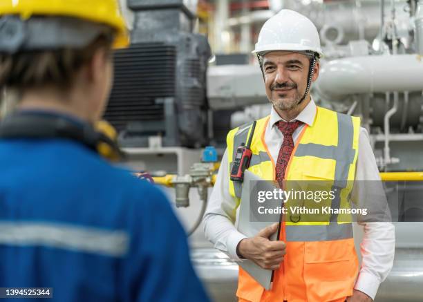 engineer working at factory with pipeline and pump, engineer discuss to colleague about work , operator operation of oil and gas process at power plant - water treatment stock-fotos und bilder