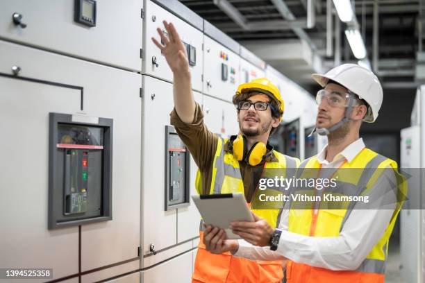 two engineer working and check status switchgear electrical energy distribution at substation room; - schaltschrank stock-fotos und bilder