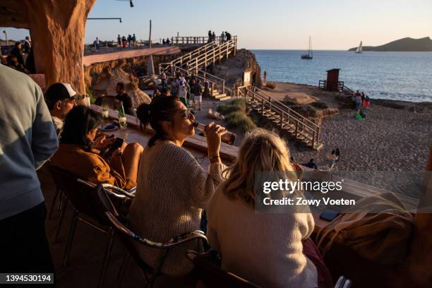 Tourists enjoy the sunset at the Sunset Ashram beach bar in Cala Comte on April 29, 2022 in Ibiza, Spain. The Spanish Mediterranean island of Ibiza,...