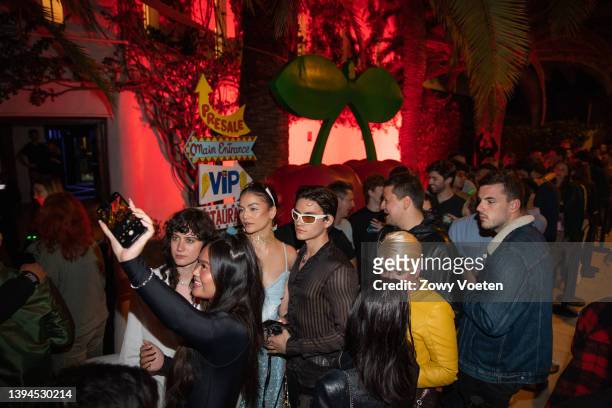 Tourists take a selfie with the Pacha disco cherry logo as they queue to get into the 2022 season opening party on April 30, 2022 in Ibiza, Spain....